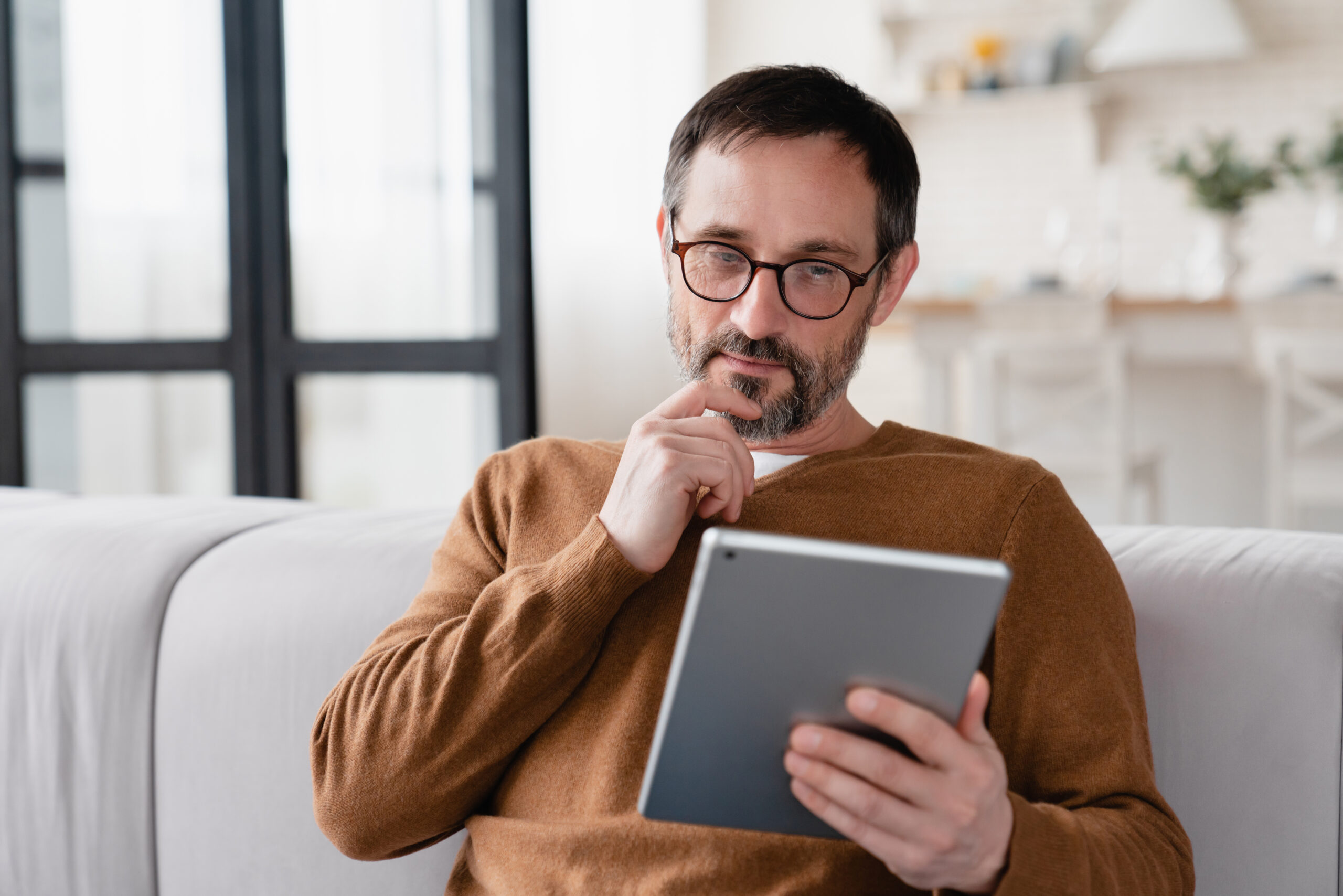 Un homme pensif étudie son certificat de prévoyance sur sa tablette en ligne